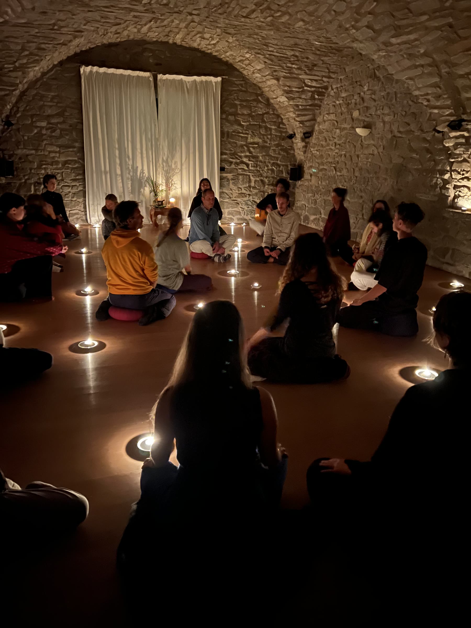 Eine Retreat-Gruppe sitzt in einem Kreis aus Kerzen im steinernen Gewölberaum des Il Convento.